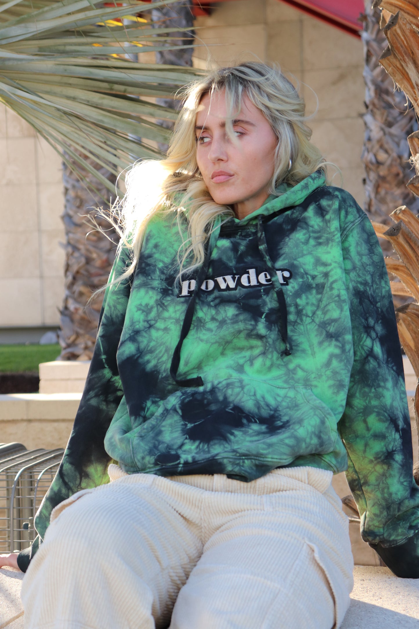 Model relaxing in a Tie Dye Green & Black PowderLA hoodie
