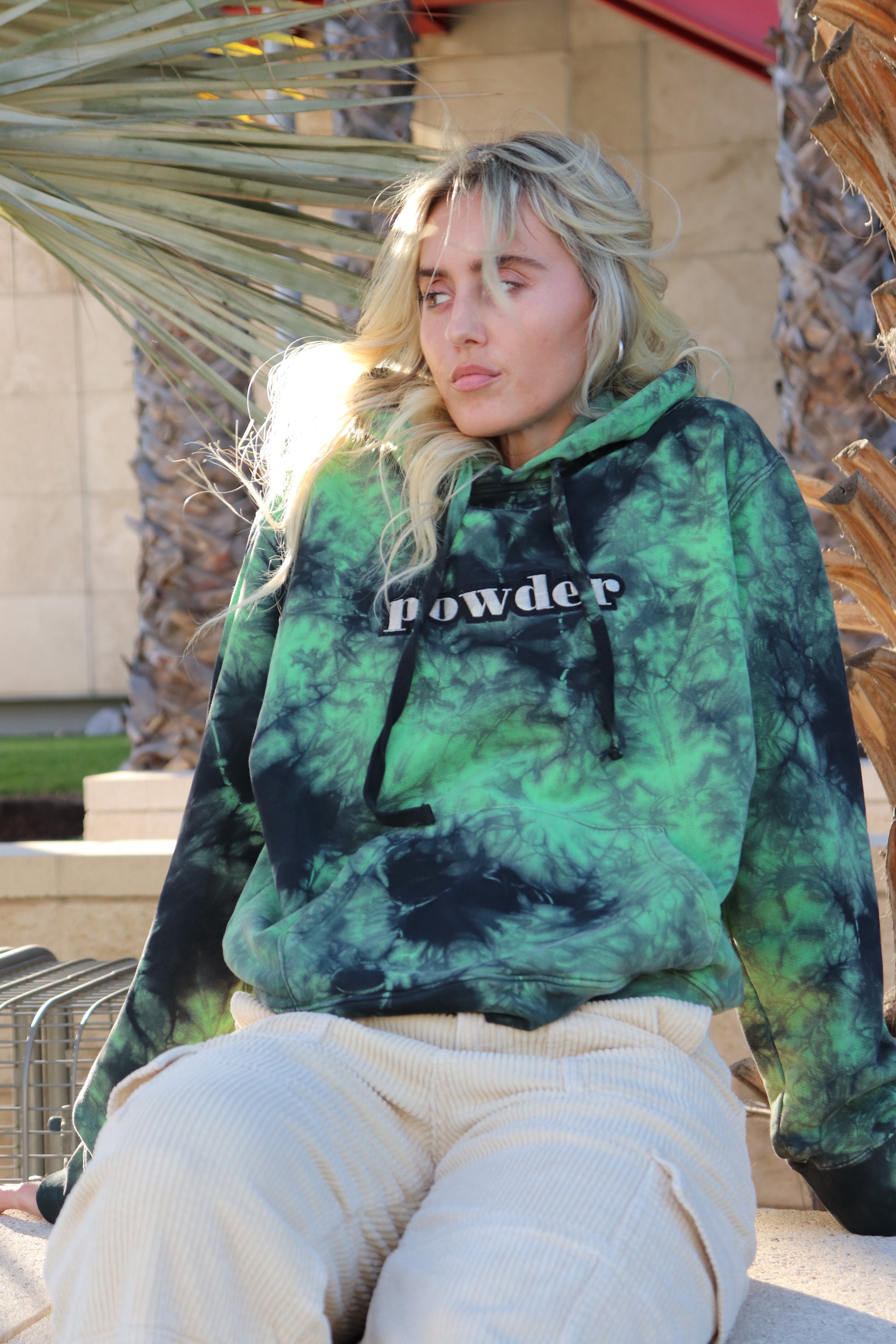 Model relaxing in a Tie Dye Green & Black PowderLA hoodie