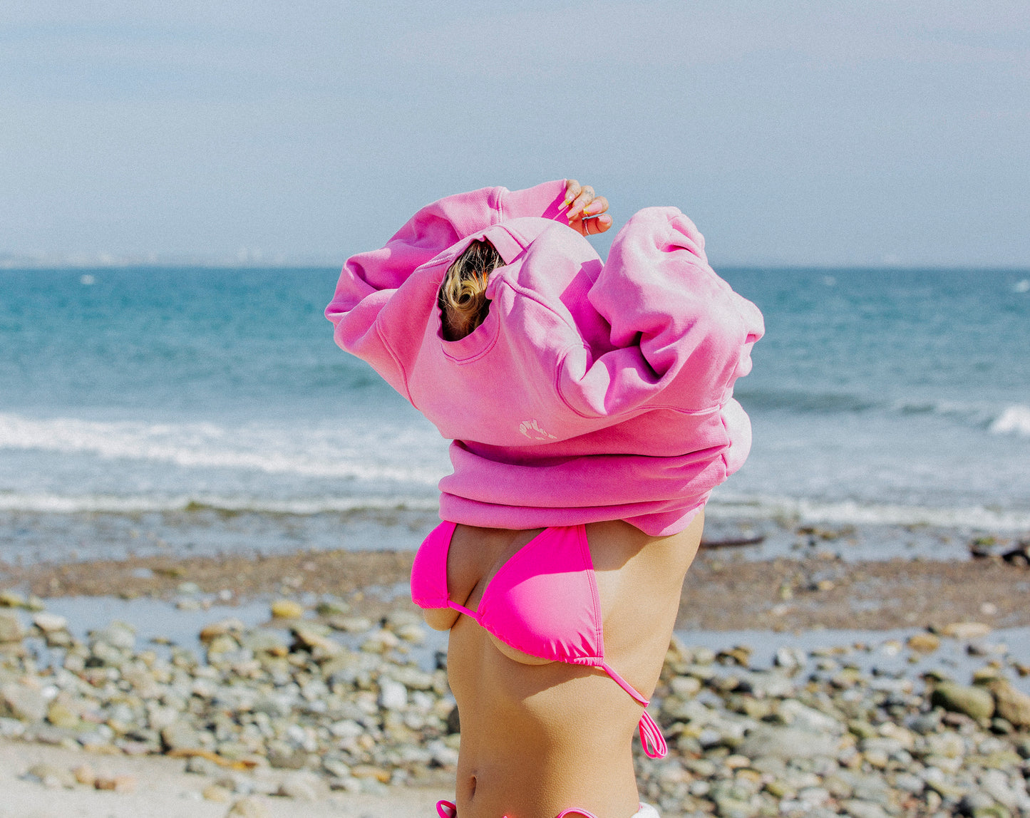 Model putting on bubblegum pink crewneck sweatshirt
