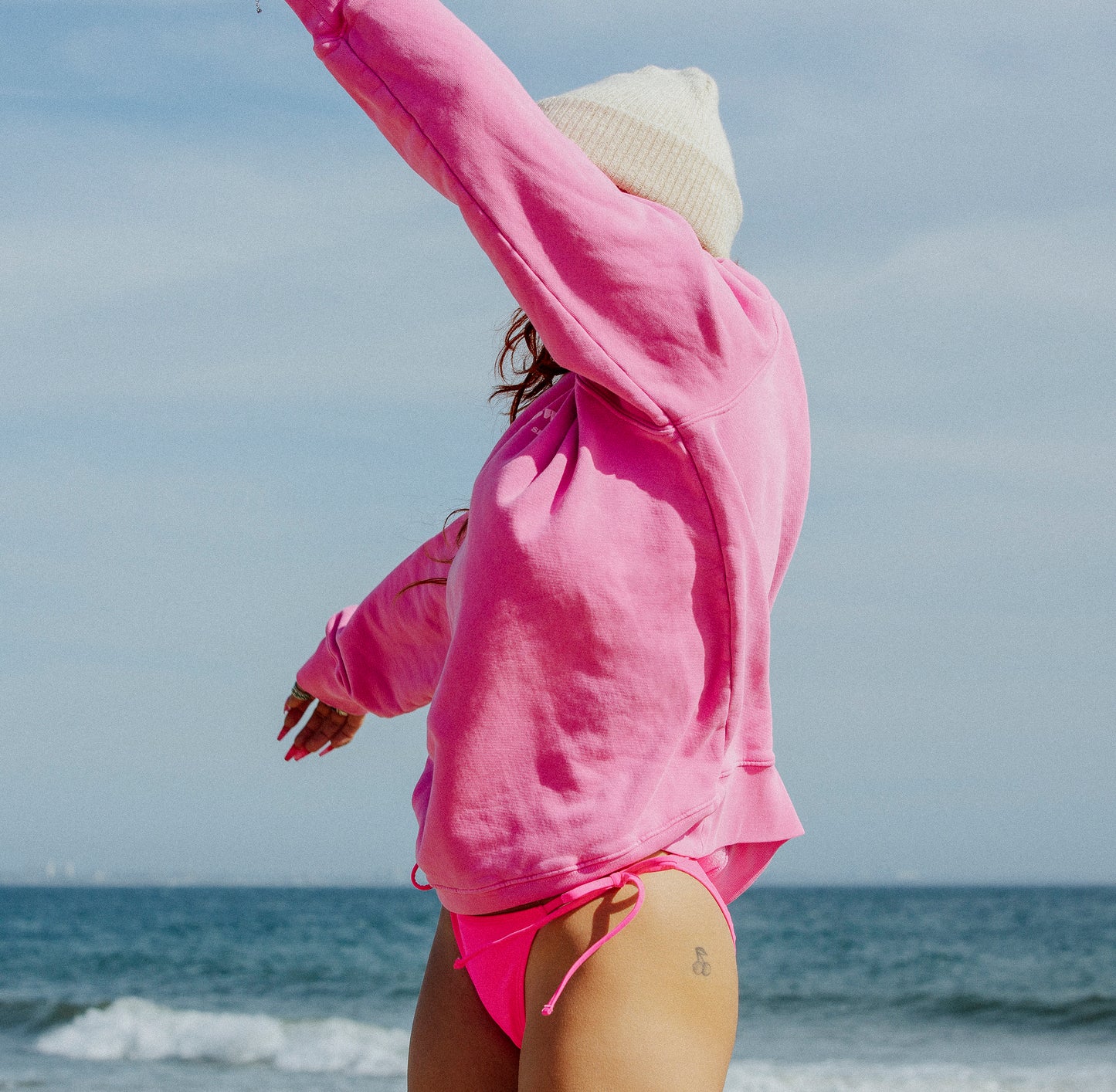 Model stretching arms in pink crewneck - surf and citywear by PowderLA