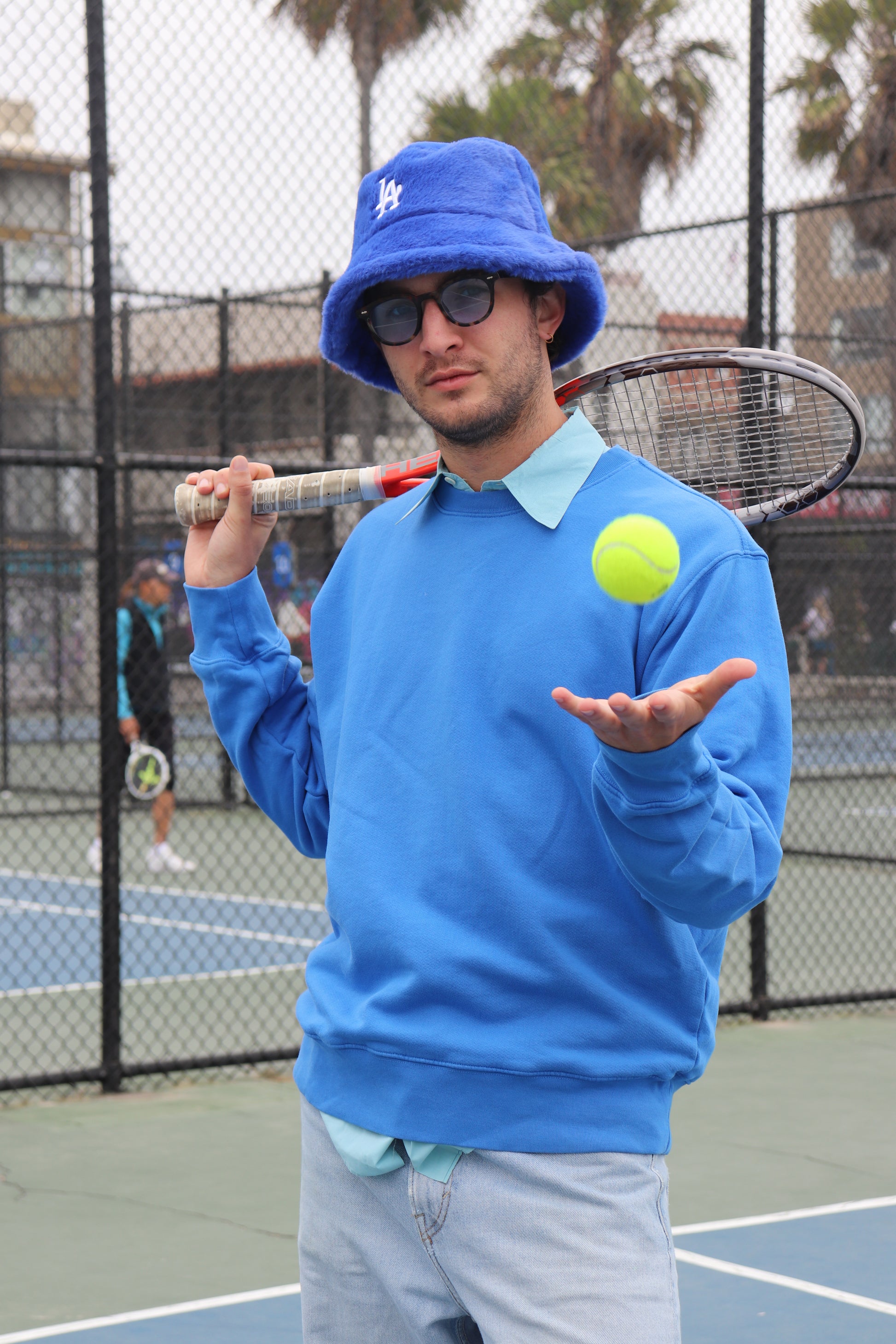 Model wearing ocean blue crewneck on tennis court
